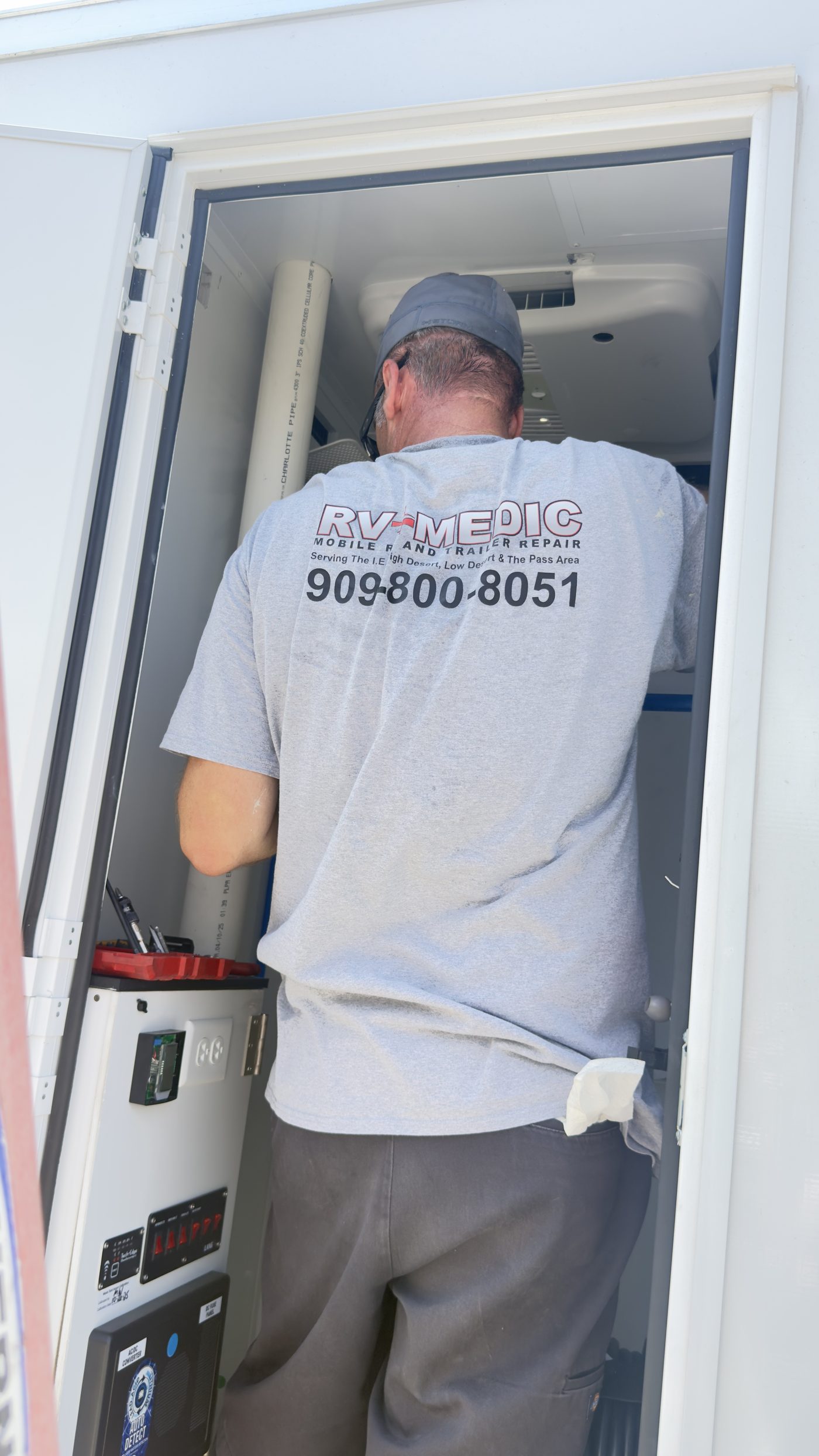 RV Medic technician repairing an RV electrical panel on-site